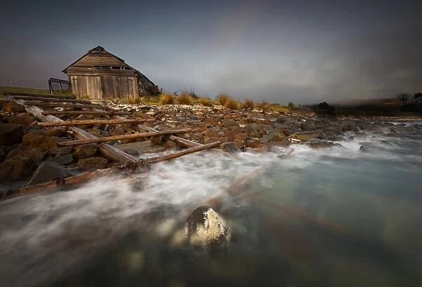 Old boat shed with waves and rocks
