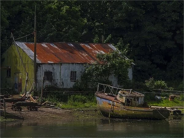 Old boatshed and derelict fishing boat moored on the river at Caernarfon, Northern Wales, United kingdom