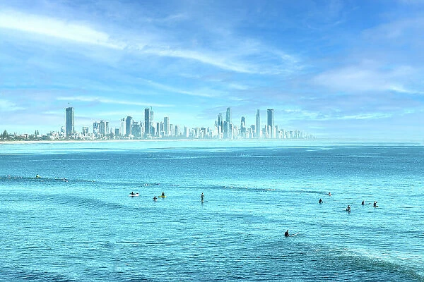 People surfing in the blue ocean waters of the Gold Coast with city skyline