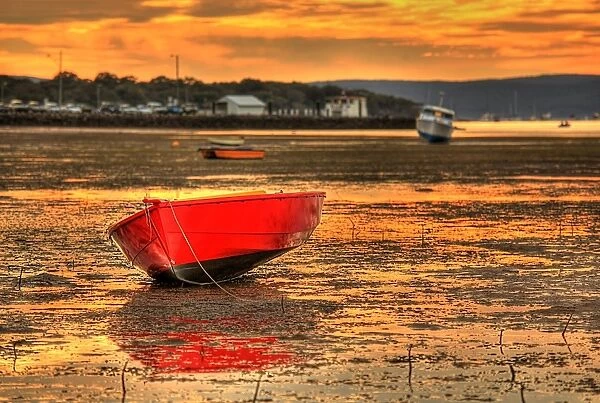 Red boat. Bright red boat in foreground on muddy shore at low tide