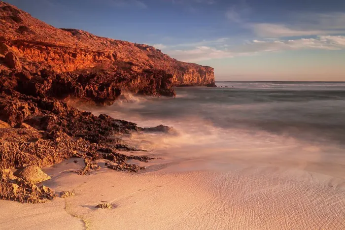 Framed Print : Red glow. Sunset on the coast with red cliffs and warm colours on the beach
