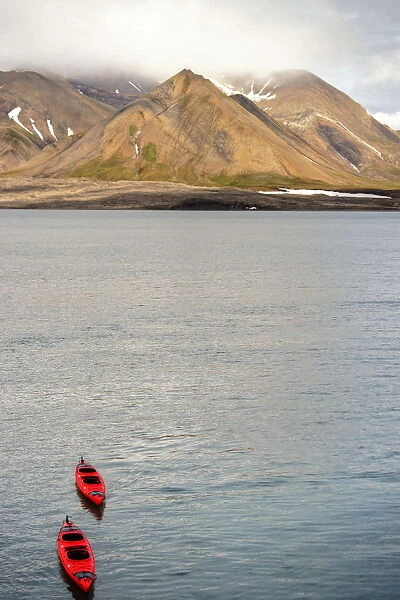 Red kayaks and Svalbard summer mountains