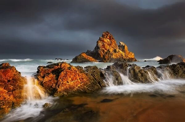 Rock seascape at sunset dark clouds