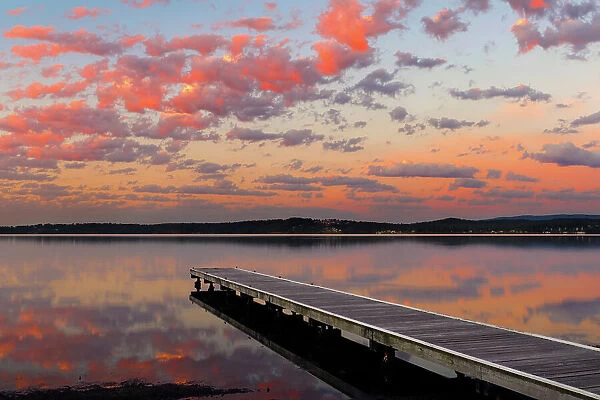 sunrise with clouds over a jetty on the lake