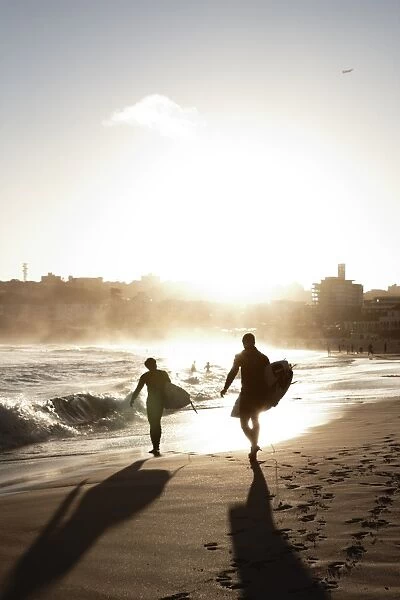 Two surfers walking along the beach