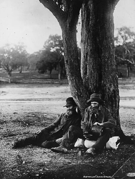 Swag Men. circa 1900: Australian sundowners sitting under a tree, one pouring