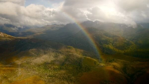 Tasmanian peaks with strong sunlight and rainbow