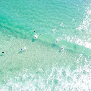 Aerial point of View crystal clear ocean waters with people surfing