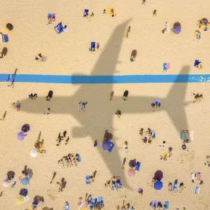 Aerial view of an airplane shadow over a crowded sandy beach