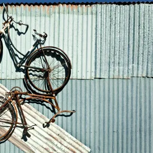 Three bike artwork hanging from a tin shed