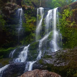 Cascading waterfall over green rocks