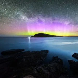 Colourful display of the Aurora Australis over an island in the ocean at Blue Hour