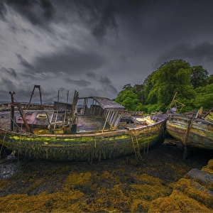 Derelict old fishing trawlers, moored along an old stone wharf on the Isle of Mull, Inner Hebrides, Scotland