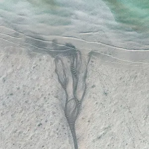 Drone image looking down on a stream of water flowing into Roebuck Bay at low tide, Broome, Western Australia, Australia Drone image looking down on a stream of water flowing into Roebuck Bay at low tide, Broome, Western Australia, Australia