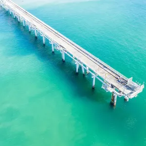 Drone view of a Long sand pumping jetty out into the clear ocean water