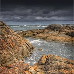 Half moon bay on the West coastline of King Island, has large rock-pools and magnificent red coloured lichen boulders of pink granite. Bass Strait, Tasmania