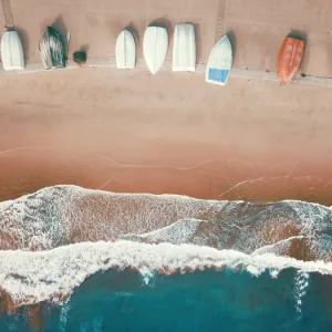 Vue d'angle élevé de petits bateaux alignés sur une plage sablonneuse.