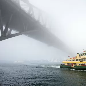 Iconic Sydney Ferry passing the Bridge on a misty day