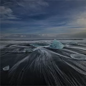 Jokulsarlon Beach in winter, just after a huge storm hit the coastline. Ice bergs from the nearby lagoon have been swept up onto the coastline and surge in and out with the tide
