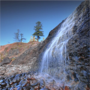 A low angled view of the lower Cockpit falls, which cascade over a steep cliff onto rocks, right on the coastline at Norfolk Island