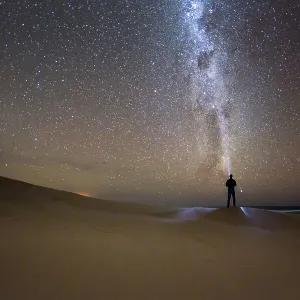 Man shining a light into space. Milky Way. Seaford Bay sand dunes. South Australia Man shining a light into space. Milky Way. Seaford Bay sand dunes. South Australia