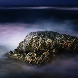 A Night View of a Rock in the Middle of the Sea Waves in a Long Exposure View