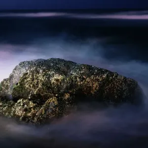 A Night View of a Rock in the Middle of the Sea Waves in a Long Exposure View A Night View of a Rock in the Middle of the Sea Waves in a Long Exposure View