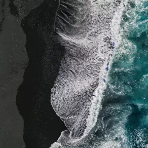 Ocean waves crashing onto volcanic sands as seen from above, Lanzarote