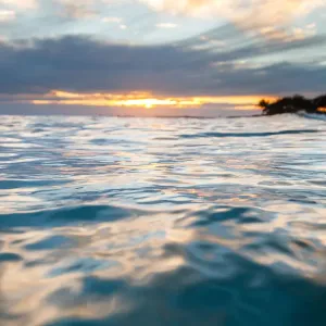 Sunrise in the water seeing the first light hit the ripples on the ocean surface Sunrise in the water seeing the first light hit the ripples on the ocean surface