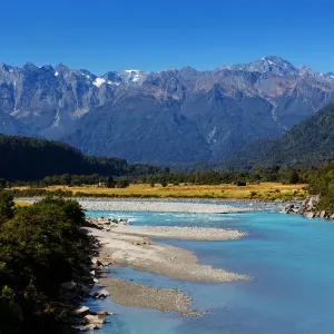 Turquoise-colored Whataroa River with snowcapped Southern Alps on horizon on autumn Turquoise-colored Whataroa River with snowcapped Southern Alps on horizon on autumn