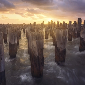 Waves breaking through wooden pier pilings in Port Melbourne, Australia