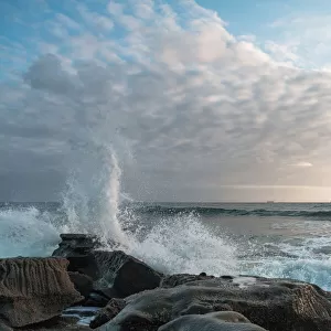 White clouds with waves crashing on a rock formation at Moffat Beach, Queensland
