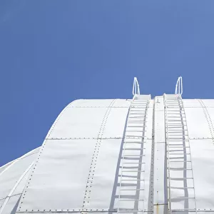 White round roof of a old building structure with stairs up to the top against a clear