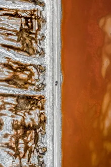 Aerial shot of an dirt track and a truck alongside vibrant coloured salt ponds Aerial shot of an dirt track and a truck alongside vibrant coloured salt ponds