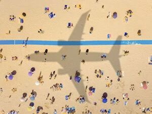 Felix Cesare Collection: Aerial view of an airplane shadow over a crowded sandy beach
