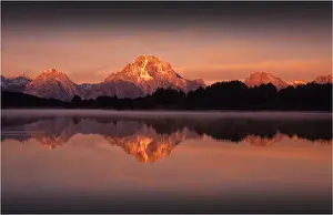 A beautiful coloured dawn casts its glow over Jackson lake in the Grand Tetons, Wyoming