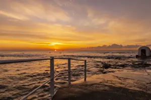Beautiful red, yellow and orange colors of a sunrise over the ocean and oceans pools