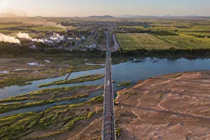 <b class=qtipBold><figcaption>Burdekin bridge</figcaption></b><br>Aerial view of a bridge across a large river in the morning light looking across to a small town and a sugar mill.<br><em>© Phil Copp</em> Burdekin bridge