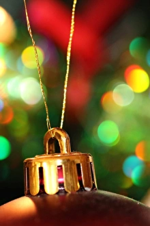 Christmas decoration hanging on a tree with lights in the background