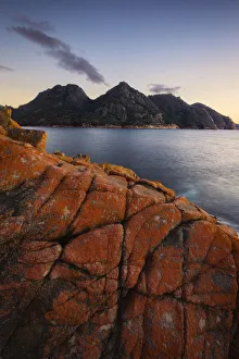 Dawn over Wineglas Bay and a section of rock covered in red lichen with the Hazards Dawn over Wineglas Bay and a section of rock covered in red lichen with the Hazards