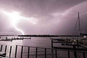 Lightning Strikes Collection: Flashes of bright lightning strikes across the water with boats silhouetted