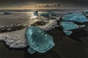 Jokulsarlon Beach in winter, just after a huge storm hit the coastline. Ice bergs from the nearby lagoon have been swept up onto the coastline and surge in and out with the tide