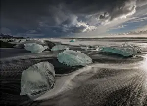 Jokulsarlon Beach in winter, just after a huge storm hit the coastline. Ice bergs from the nearby lagoon have been swept up onto the coastline and surge in and out with the tide