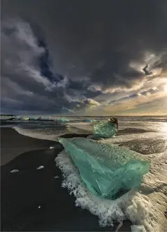 Jokulsarlon Beach in winter, just after a huge storm hit the coastline. Ice bergs from the nearby lagoon have been swept up onto the coastline and surge in and out with the tide