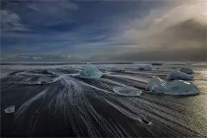 Jokulsarlon Beach in winter, just after a huge storm hit the coastline. Ice bergs from the nearby lagoon have been swept up onto the coastline and surge in and out with the tide
