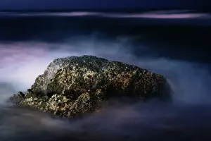 Prints of A night view of a rock in the middle of the sea waves in a long exposure view. The waves looked like a purple-blue tone smoke in the picture Queensland (QLD) Prints: A Night View of a Rock in the Middle of the Sea Waves in a Long Exposure View