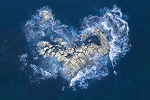 Ocean Wave Aerials Collection: Ocean waves crashing over heart-shaped rock island