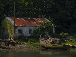 Wales Prints: Old boatshed and derelict fishing boat moored on the river at Caernarfon