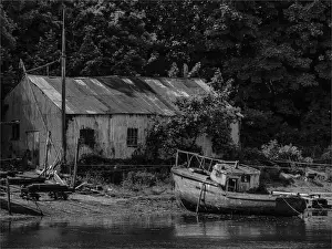 Wales Prints: Old boatshed and derelict fishing boat moored on the river at Caernarfon