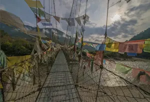 Bridge Man Made Structure Prints: Prayer flags flutter in the breeze on a suspended footbridge over the Punakha river